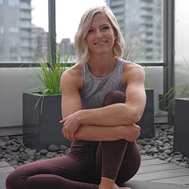 Marie Holowaychuk sitting in a wellness room with plants and rocks in an apartment.