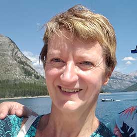 Sandra McFadyen smiling in front of a lake in the sunshine.