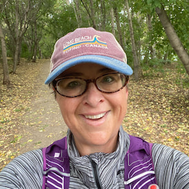 Samantha's selfie with a big smile, and she is hiking in the woods.