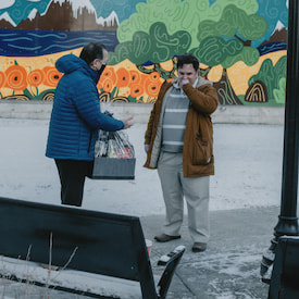 steven is carrying a gift box and chating with his friend.